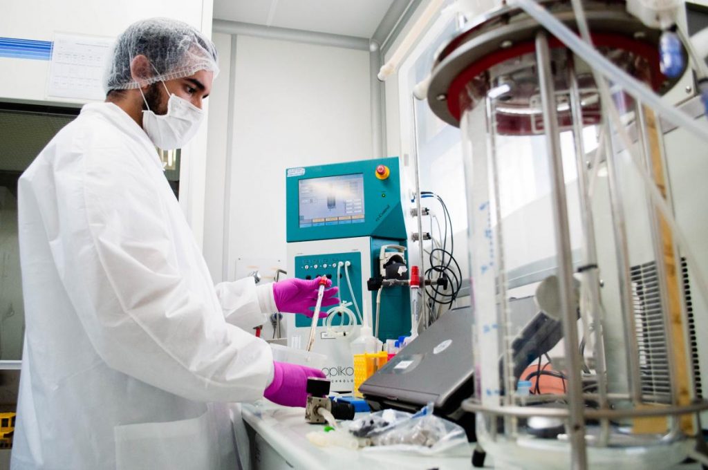Homem com touca e máscara manipula instrumentos em laboratório
